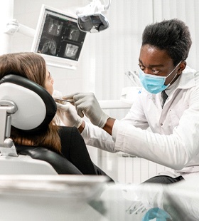 A dentist examines a patient’s smile during an appointment to determine how best to remove the amalgam fillings