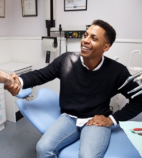 A male patient shakes hands with a dentist after having more aesthetically pleasing fillings put into place