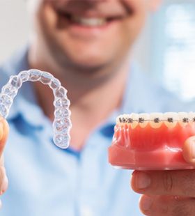 Person holding Invisalign and metal braces  