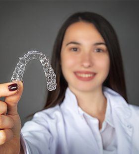 Smiling woman holding up an Invisalign tray