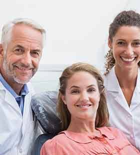 Female patient smiling with dentist and team member