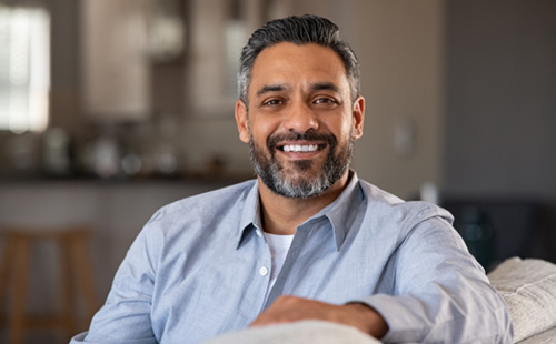 Middle-aged man seated on couch and smiling after using Homeoblock in