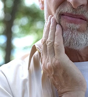 Man holding his cheek because of tooth pain